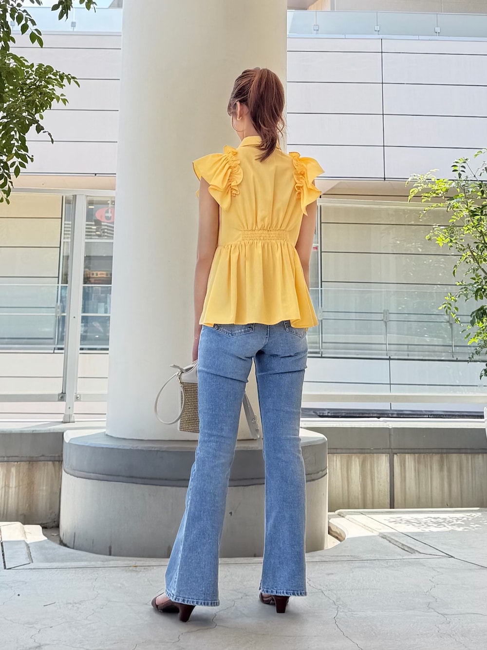 イエロー系のシャツ/ブラウス、ホワイト系のショルダーバッグ、ブルー系のデニムパンツを着用したレディースの夏コーディネートの5枚目の写真