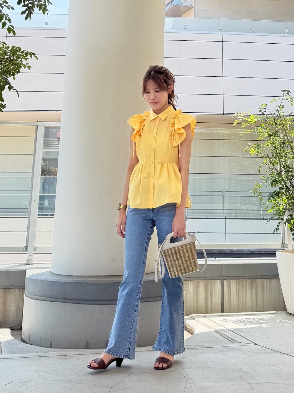 イエロー系のシャツ/ブラウス、ホワイト系のショルダーバッグ、ブルー系のデニムパンツを着用したレディースの夏コーディネートの2枚目の写真