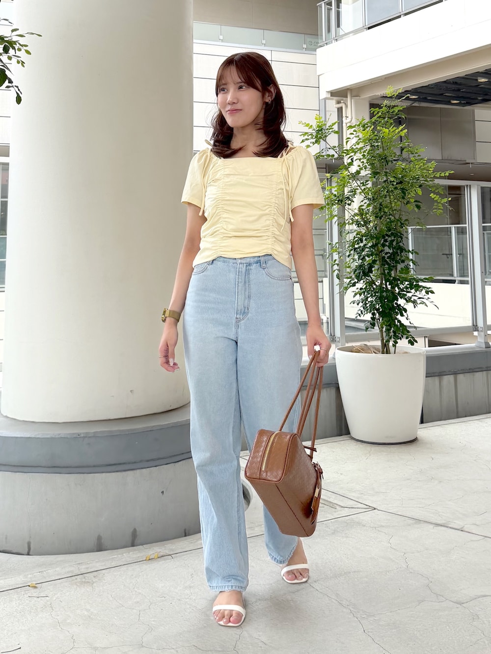 イエロー系のTシャツ/カットソー、ブルー系のデニムパンツ、ブラウン系のボストンバッグを着用したレディースの夏コーディネートの2枚目の写真