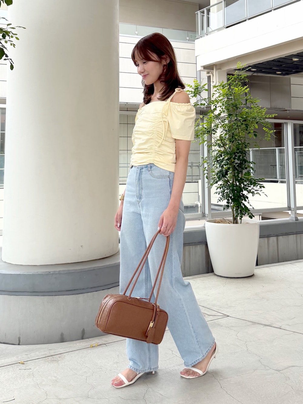イエロー系のTシャツ/カットソー、ブルー系のデニムパンツ、ブラウン系のボストンバッグを着用したレディースの夏コーディネートの3枚目の写真