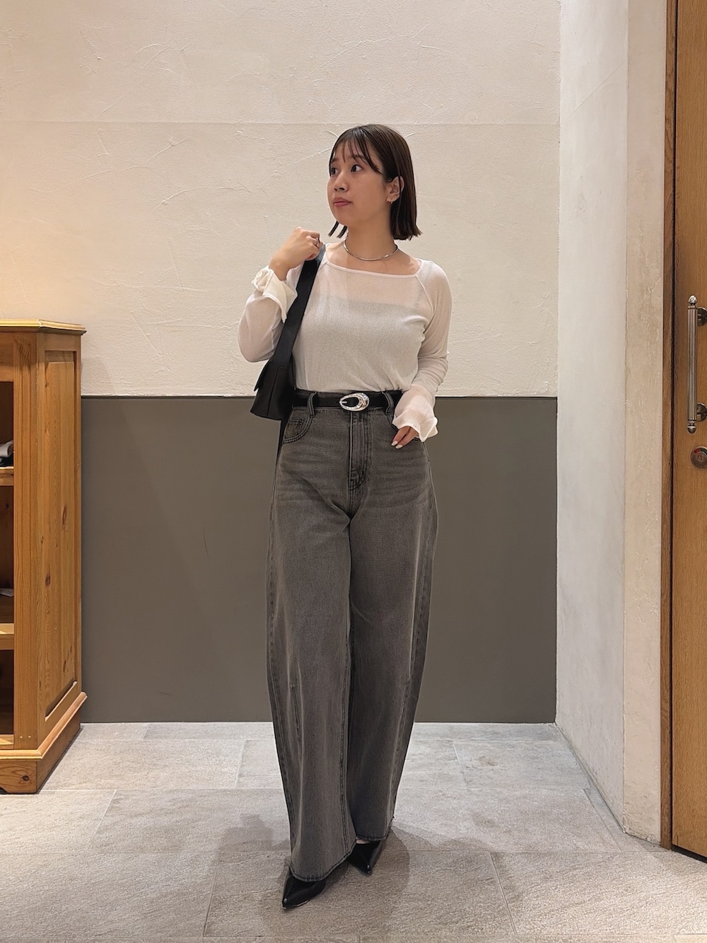 ブラック系のデニムパンツ、ブラック系のショルダーバッグ、ホワイト系のTシャツ/カットソーを着用したレディースの秋コーディネートの2枚目の写真