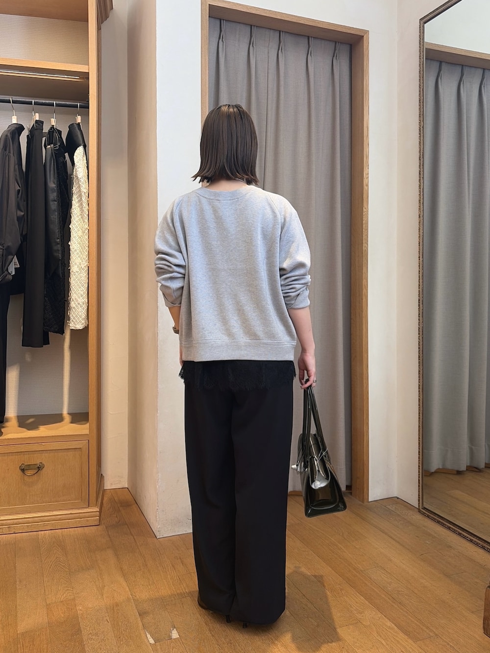 ブラック系のスラックス、グレー系のニット/セーター、ブルー系のシャツ/ブラウスを着用したレディースの秋コーディネートの5枚目の写真