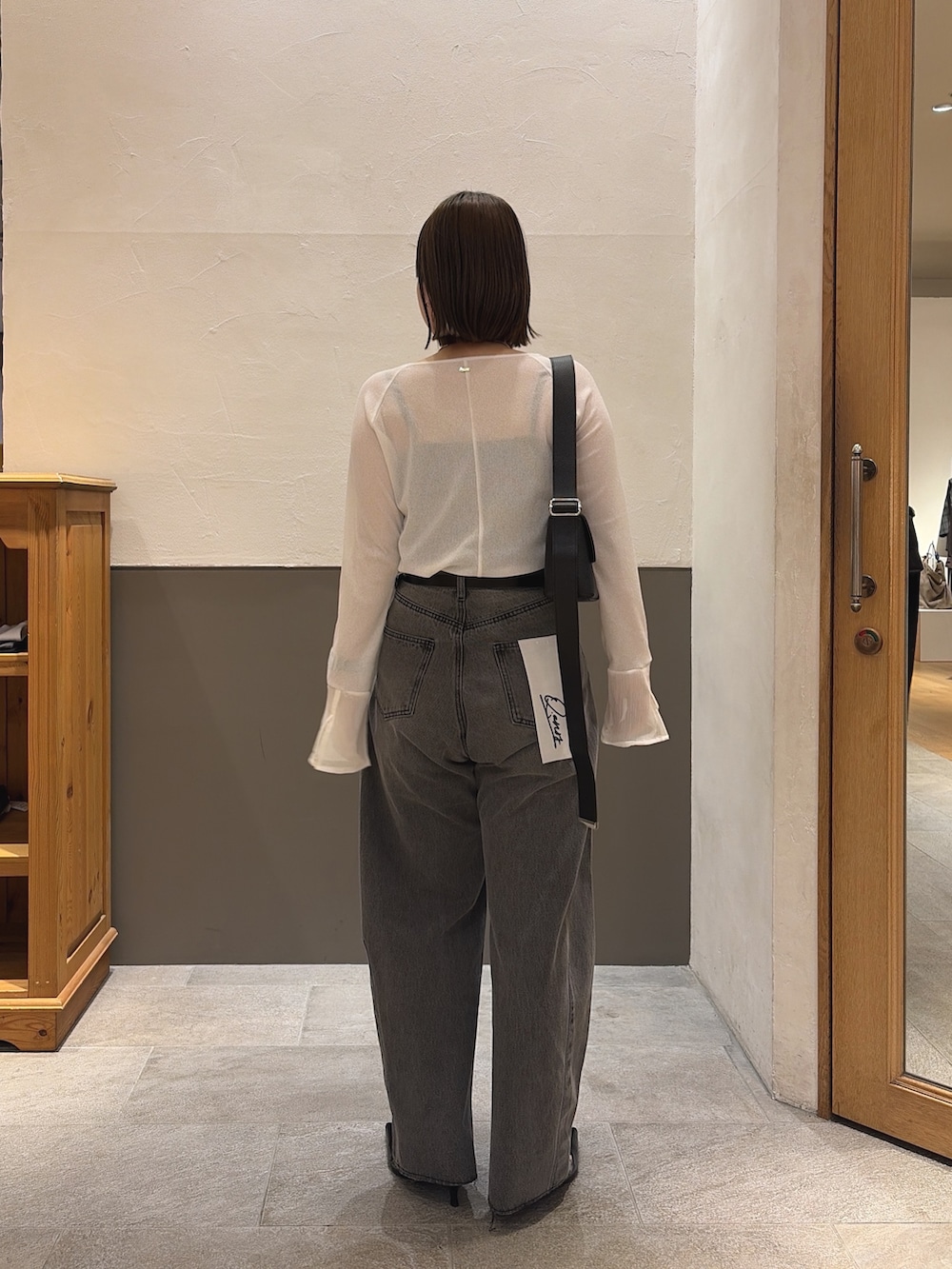 ブラック系のデニムパンツ、ブラック系のショルダーバッグ、ホワイト系のTシャツ/カットソーを着用したレディースの秋コーディネートの5枚目の写真