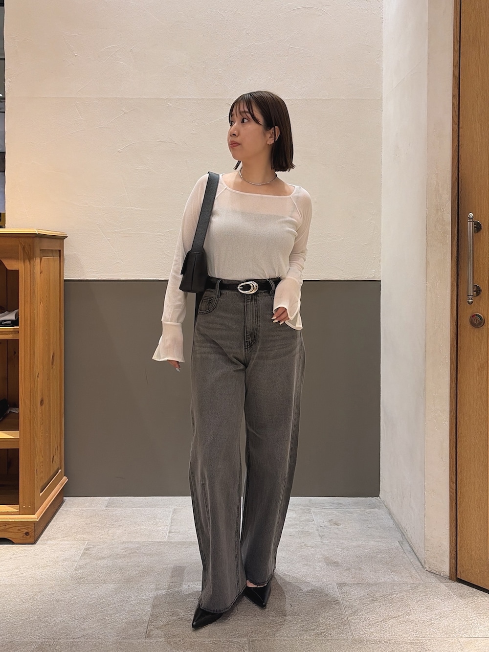 ブラック系のデニムパンツ、ブラック系のショルダーバッグ、ホワイト系のTシャツ/カットソーを着用したレディースの秋コーディネートの3枚目の写真
