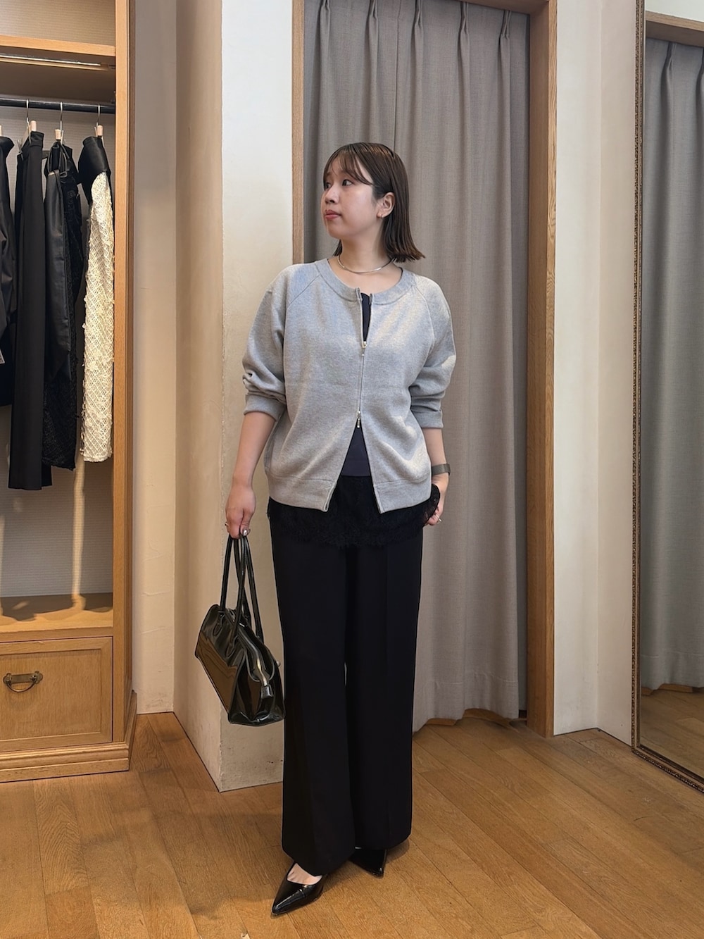 ブラック系のスラックス、グレー系のニット/セーター、ブルー系のシャツ/ブラウスを着用したレディースの秋コーディネートの2枚目の写真