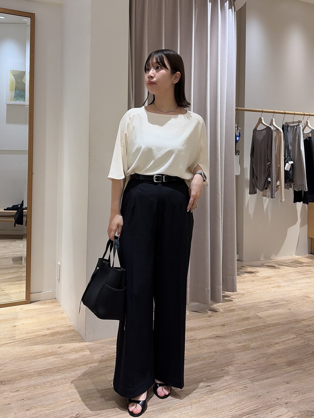 ブラック系のスラックス、ホワイト系のシャツ/ブラウス、ブラック系のトートバッグを着用したレディースの夏コーディネートの3枚目の写真