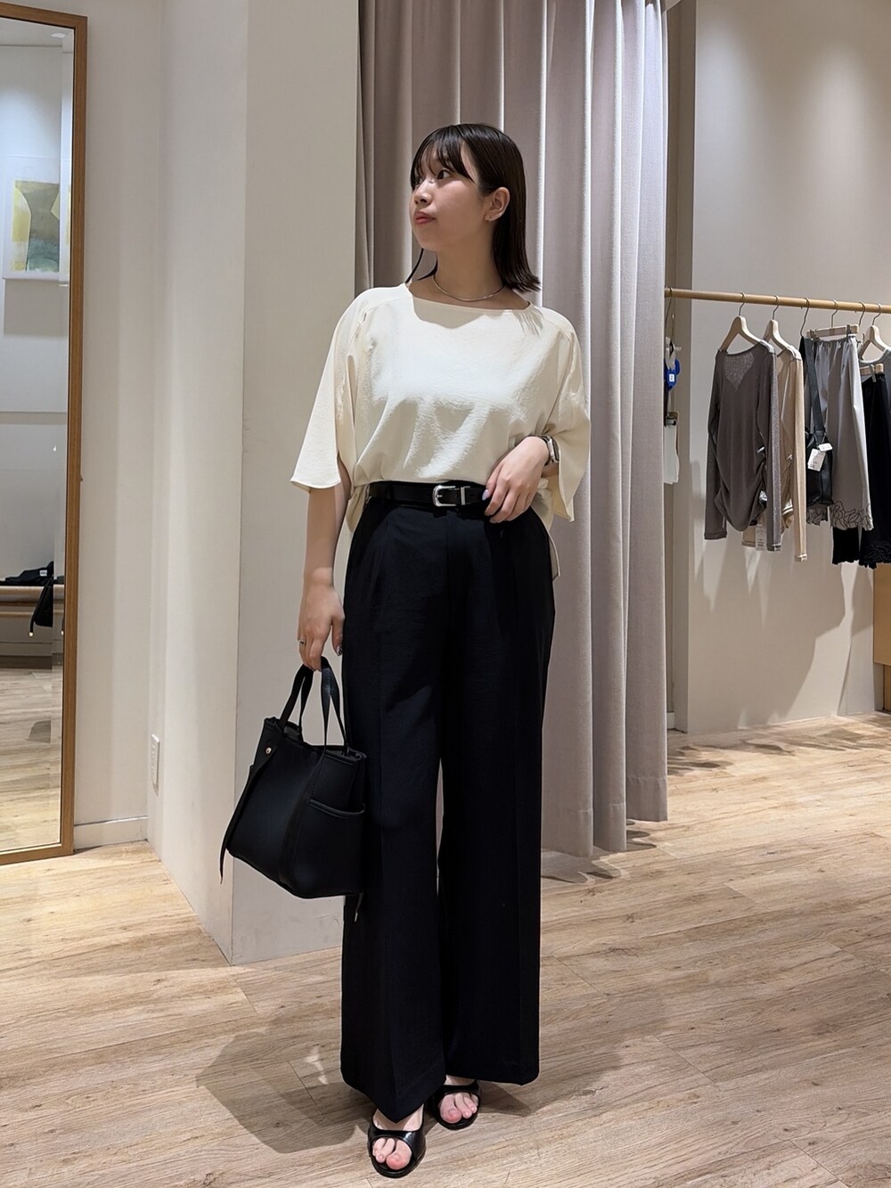 ブラック系のスラックス、ホワイト系のシャツ/ブラウス、ブラック系のトートバッグを着用したレディースの夏コーディネートの2枚目の写真