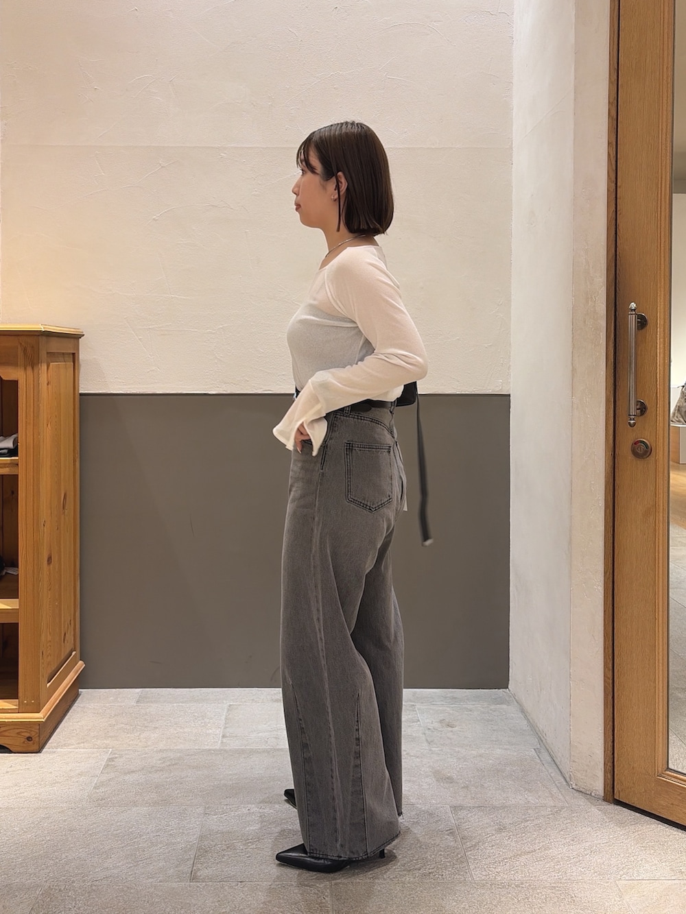ブラック系のデニムパンツ、ブラック系のショルダーバッグ、ホワイト系のTシャツ/カットソーを着用したレディースの秋コーディネートの4枚目の写真