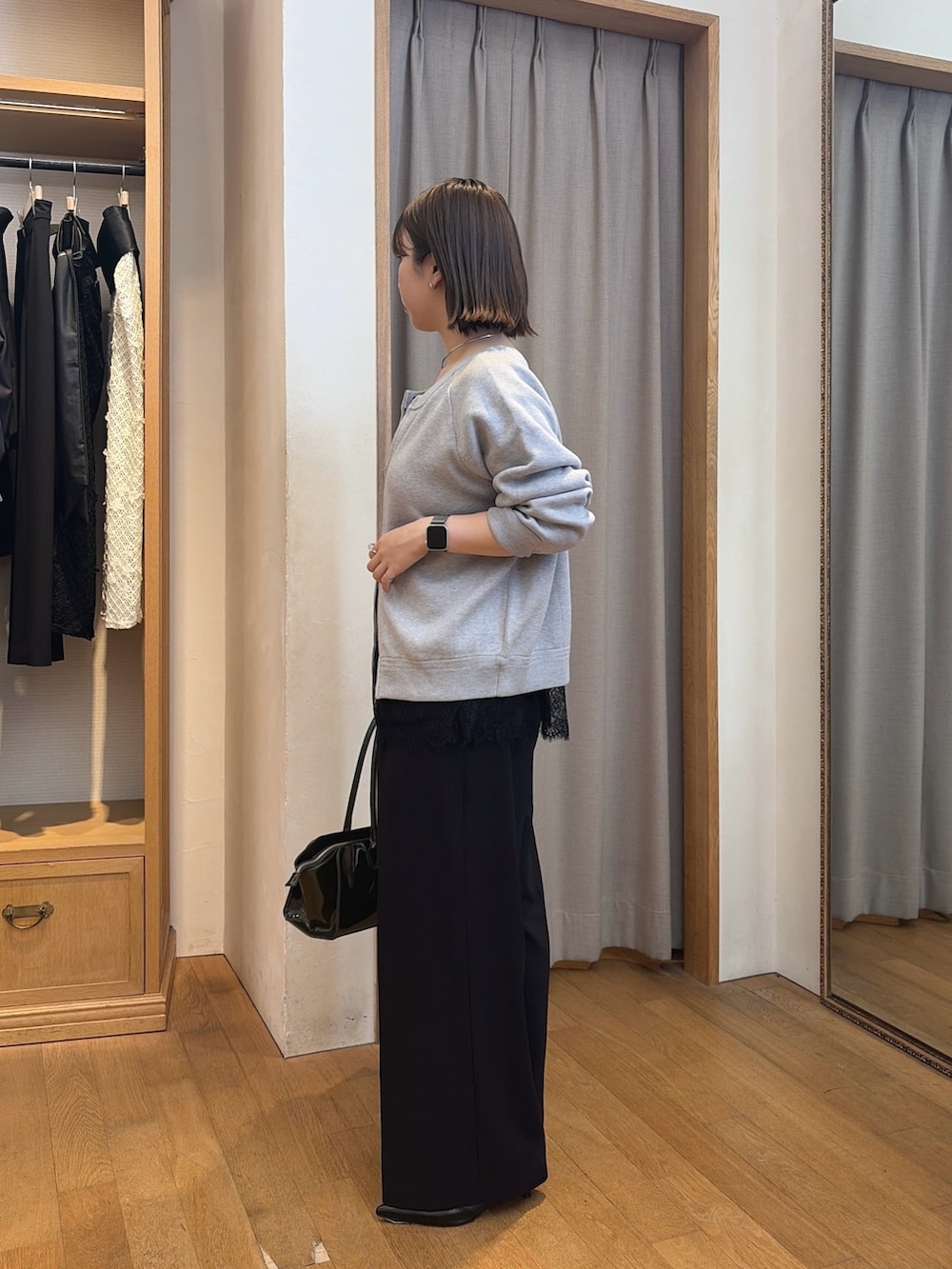 ブラック系のスラックス、グレー系のニット/セーター、ブルー系のシャツ/ブラウスを着用したレディースの秋コーディネートの3枚目の写真