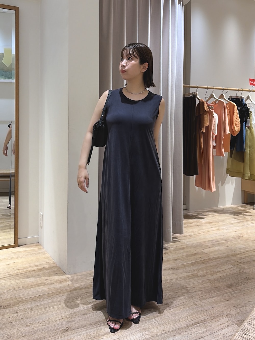 ブルー系のワンピース、ブラック系のショルダーバッグ、シルバー系のネックレスを着用したレディースの夏コーディネートの2枚目の写真