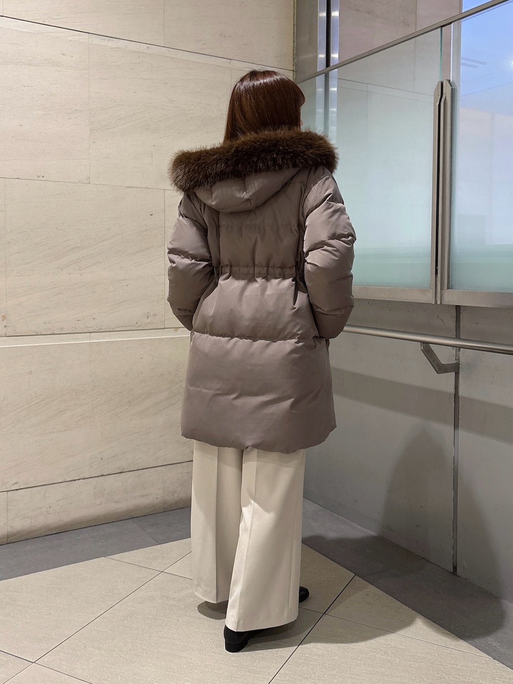 グレー系のその他パンツ、ブラウン系のダウンジャケット/コート、ホワイト系のニット/セーターを着用したレディースの秋コーディネートの4枚目の写真
