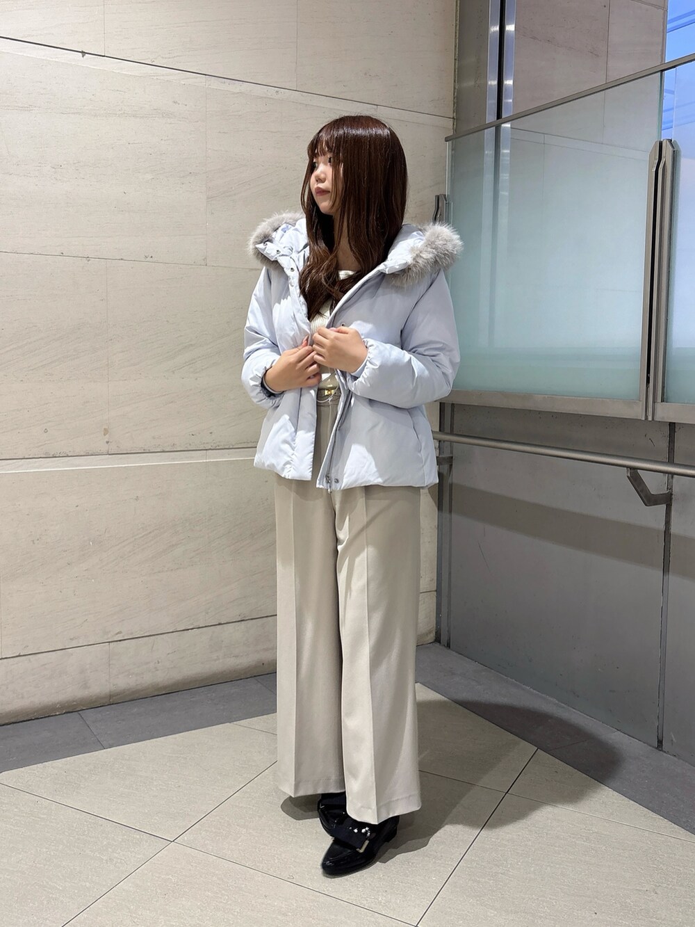 ブルー系のダウンジャケット/コート、ホワイト系のニット/セーター、グレー系のその他パンツを着用したレディースの秋コーディネートの2枚目の写真