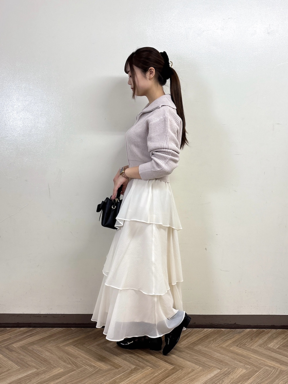 グレー系のカーディガン/ボレロ、ホワイト系のスカートを着用したレディースの秋コーディネートの4枚目の写真