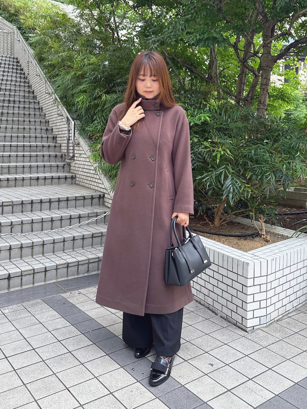 ブラウン系のチェスターコート、ブラック系のつなぎ/オールインワン、ブラック系のTシャツ/カットソーを着用したレディースの秋コーディネートの4枚目の写真