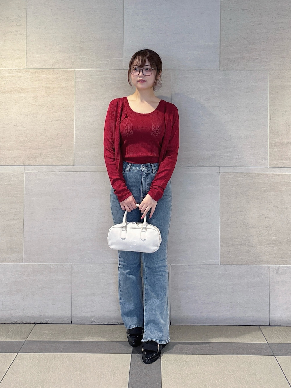 レッド系のアンサンブル、ブルー系のデニムパンツを着用したレディースの秋コーディネートの2枚目の写真
