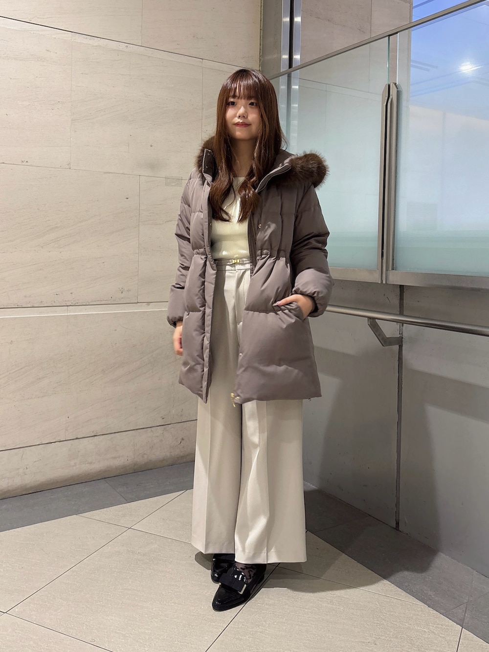 グレー系のその他パンツ、ブラウン系のダウンジャケット/コート、ホワイト系のニット/セーターを着用したレディースの秋コーディネートの3枚目の写真