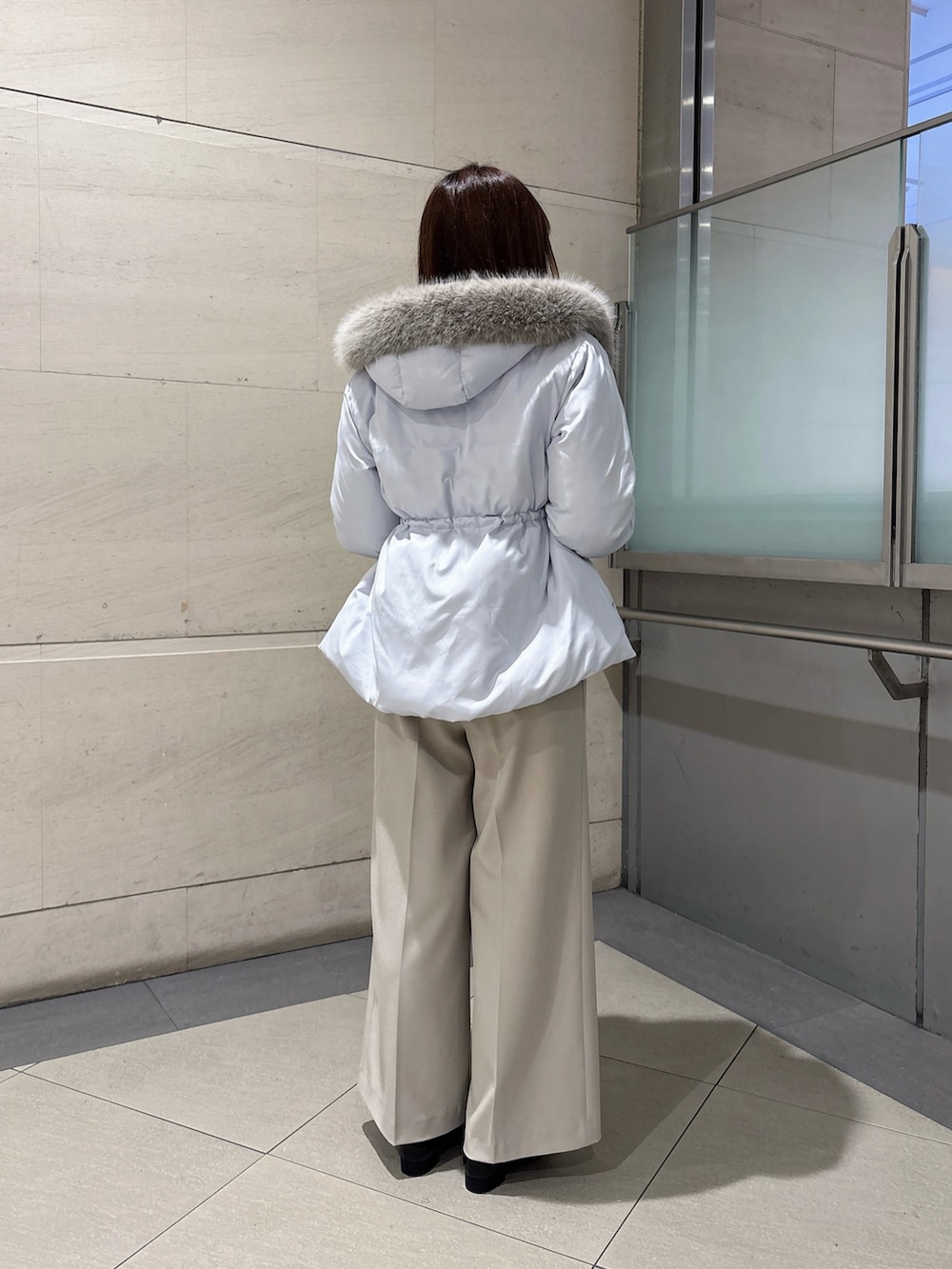ブルー系のダウンジャケット/コート、ホワイト系のニット/セーター、グレー系のその他パンツを着用したレディースの秋コーディネートの4枚目の写真