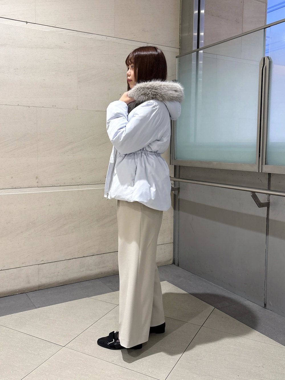 ブルー系のダウンジャケット/コート、ホワイト系のニット/セーター、グレー系のその他パンツを着用したレディースの秋コーディネートの3枚目の写真