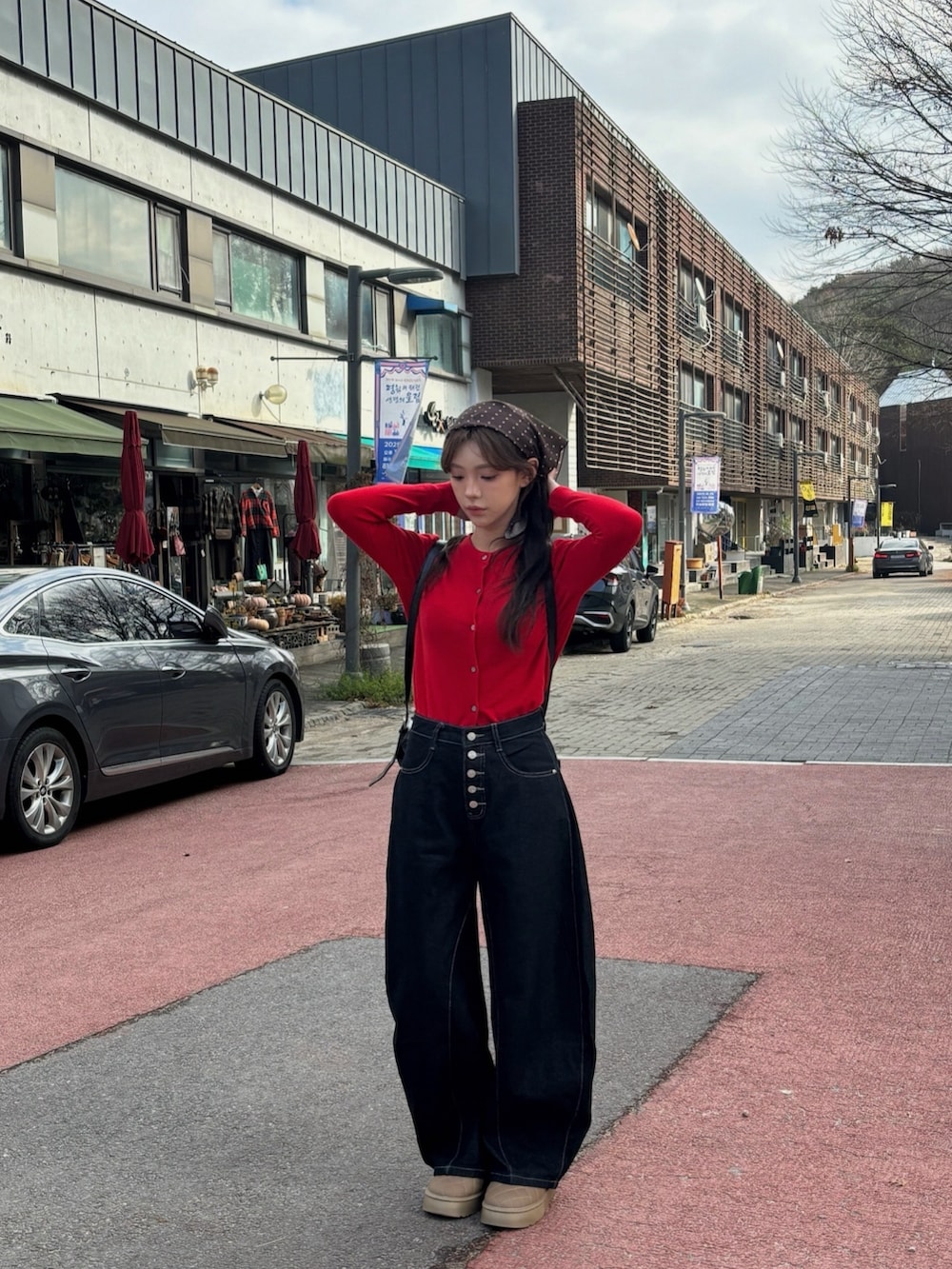 レッド系のカーディガン/ボレロ、ブラウン系のブーツ、ブラック系のデニムパンツを着用したレディースの冬コーディネートの3枚目の写真