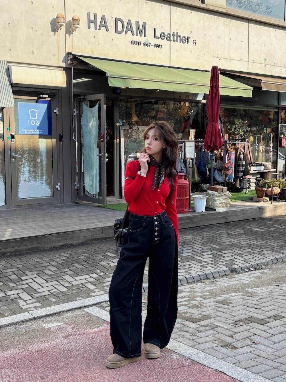 レッド系のカーディガン/ボレロ、ブラウン系のブーツ、ブラック系のデニムパンツを着用したレディースの冬コーディネートの2枚目の写真