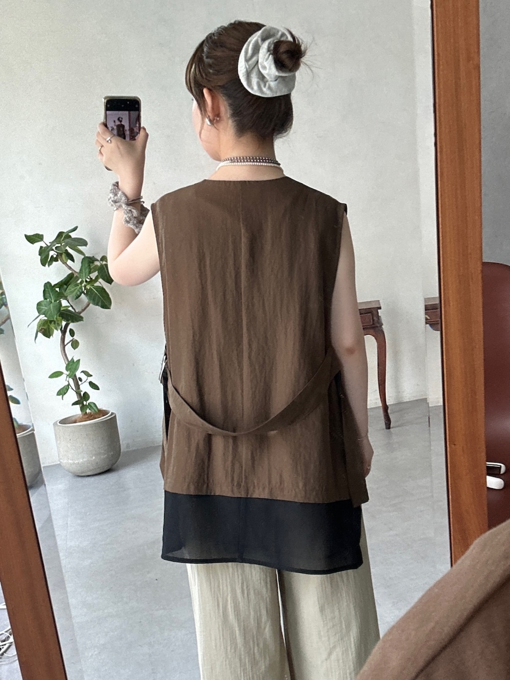 イエロー系のスカート、ブラック系のブーツ、ブラウン系のベストを着用したレディースの夏コーディネートの4枚目の写真