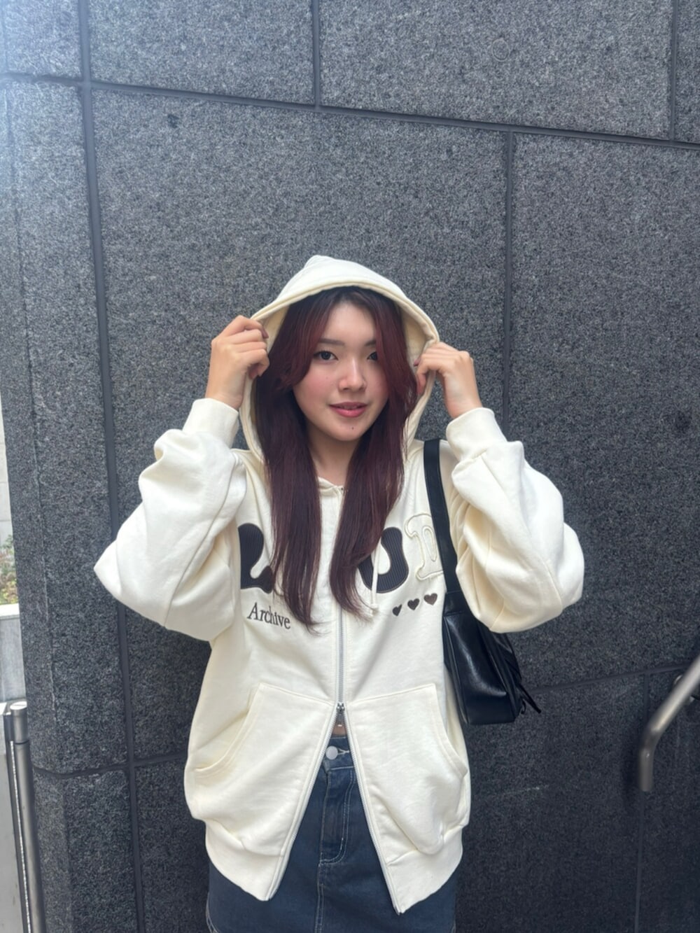 ブラック系のショルダーバッグ、ホワイト系のパーカー、ブルー系のスカートを着用したレディースの冬コーディネートの4枚目の写真