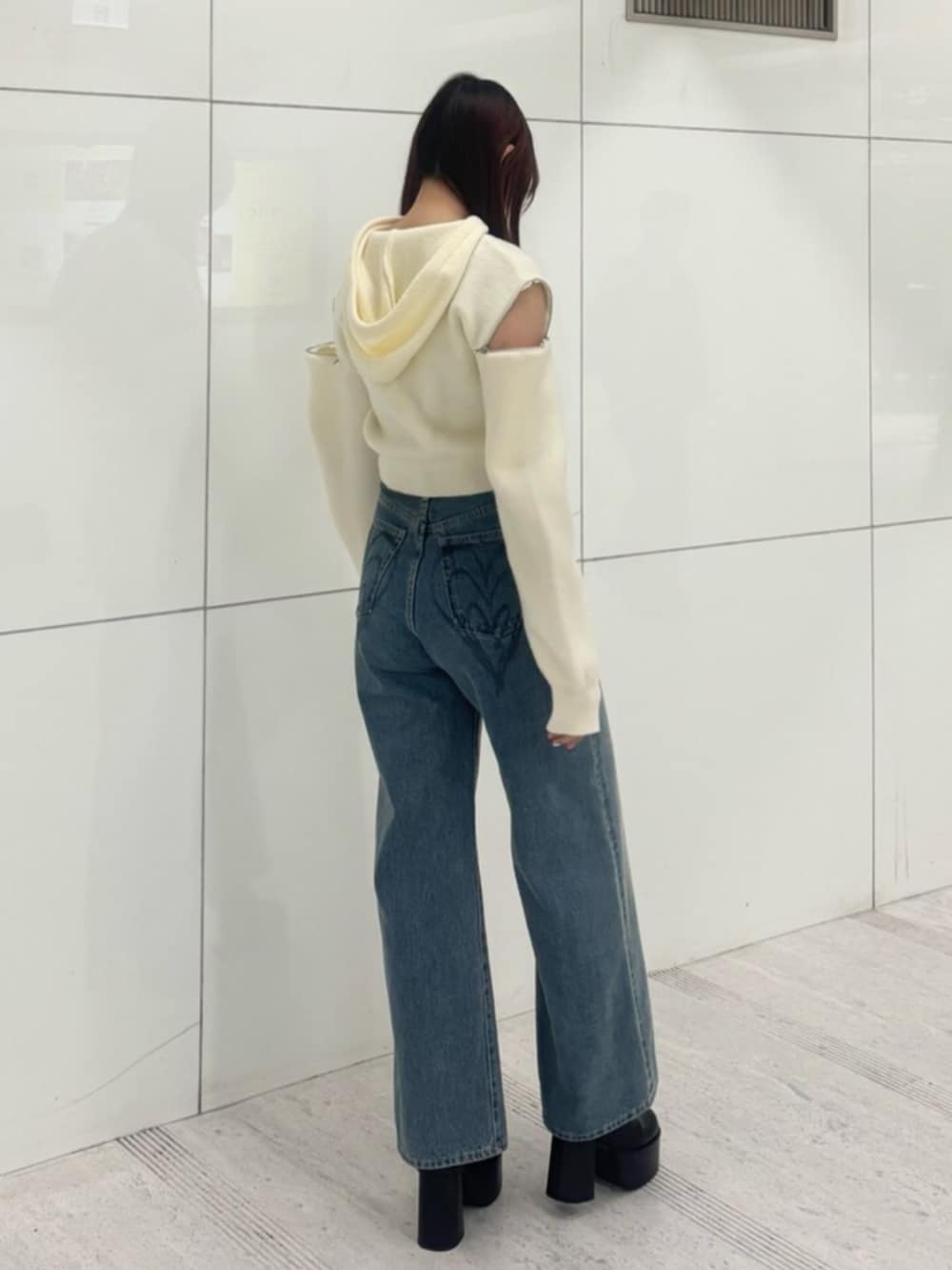 ブラック系のブーツ、ホワイト系のパーカー、ブルー系のデニムパンツを着用したレディースの冬コーディネートの3枚目の写真