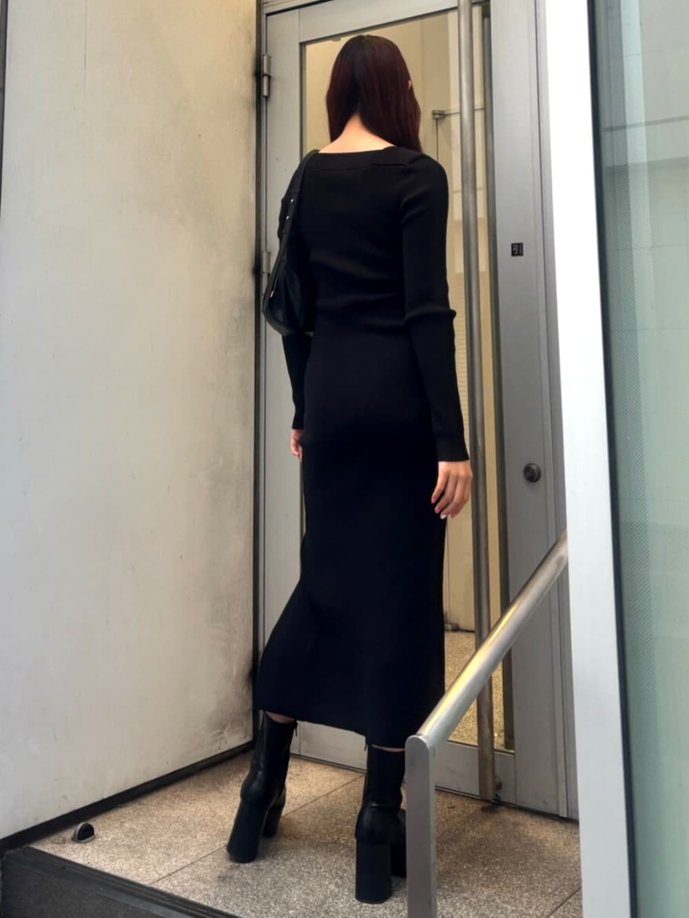 ブラック系のブーツ、ブラック系のワンピース、ブラック系のショルダーバッグを着用したレディースの冬コーディネートの3枚目の写真