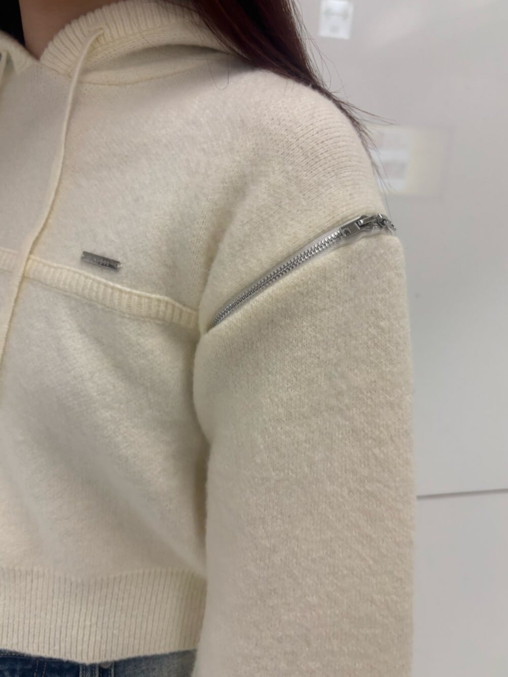 ブラック系のブーツ、ホワイト系のパーカー、ブルー系のデニムパンツを着用したレディースの冬コーディネートの7枚目の写真