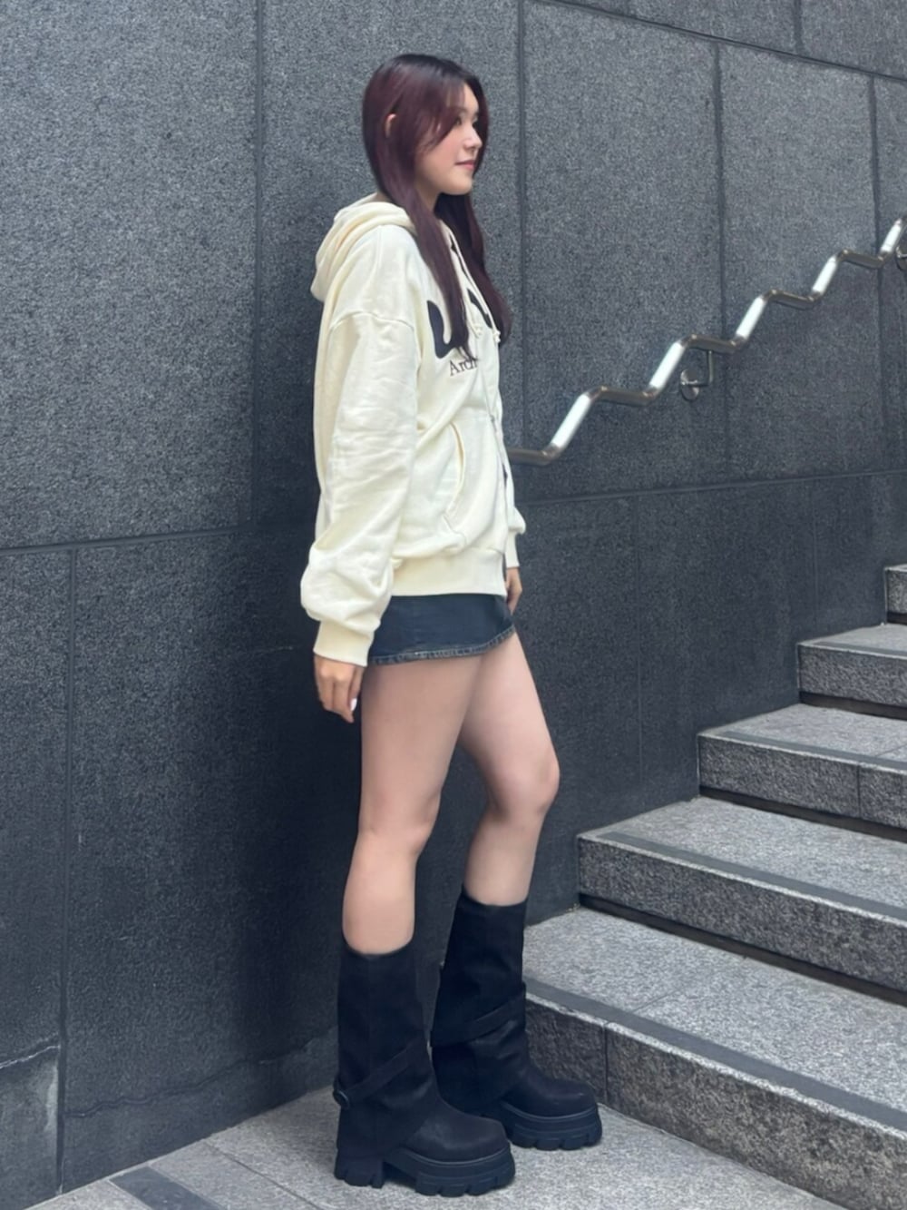 ブラック系のショルダーバッグ、ホワイト系のパーカー、ブルー系のスカートを着用したレディースの冬コーディネートの3枚目の写真