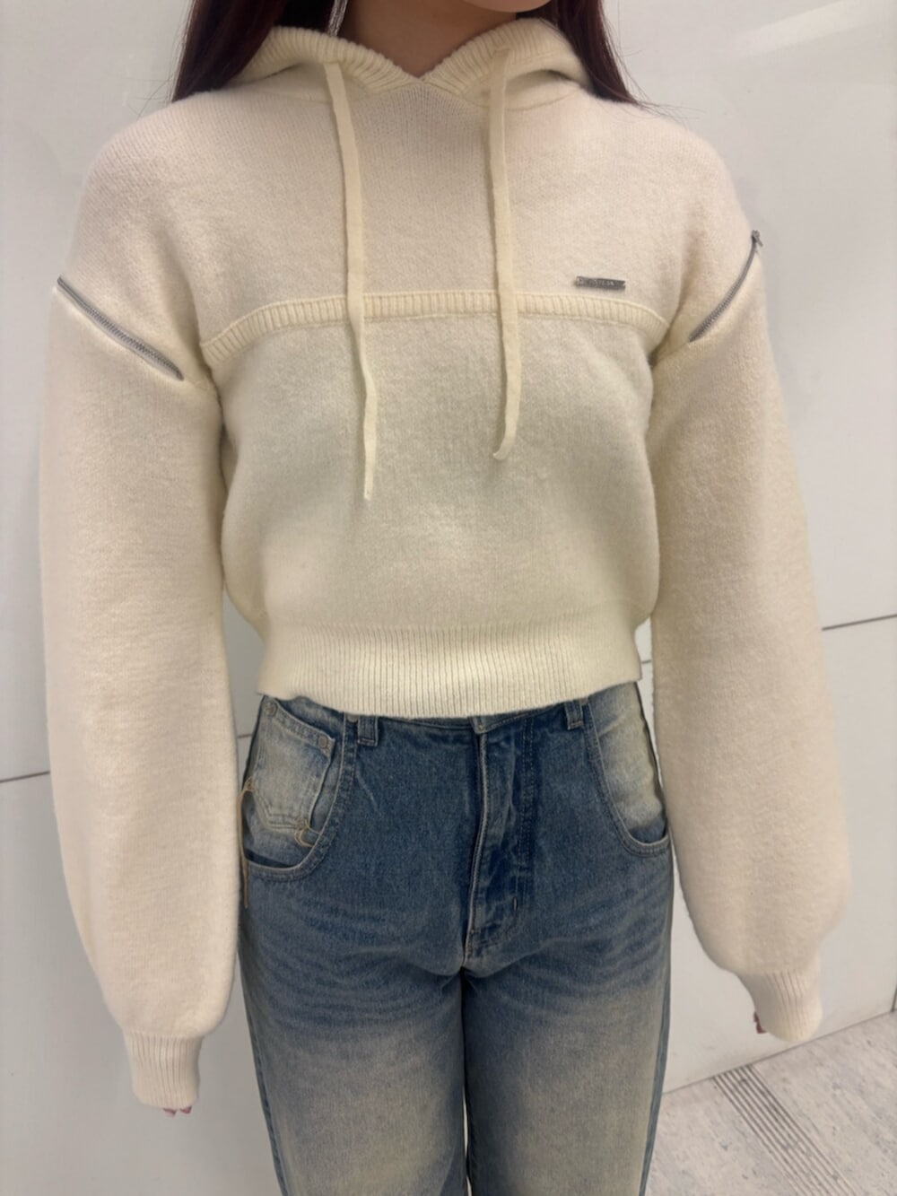 ブラック系のブーツ、ホワイト系のパーカー、ブルー系のデニムパンツを着用したレディースの冬コーディネートの5枚目の写真