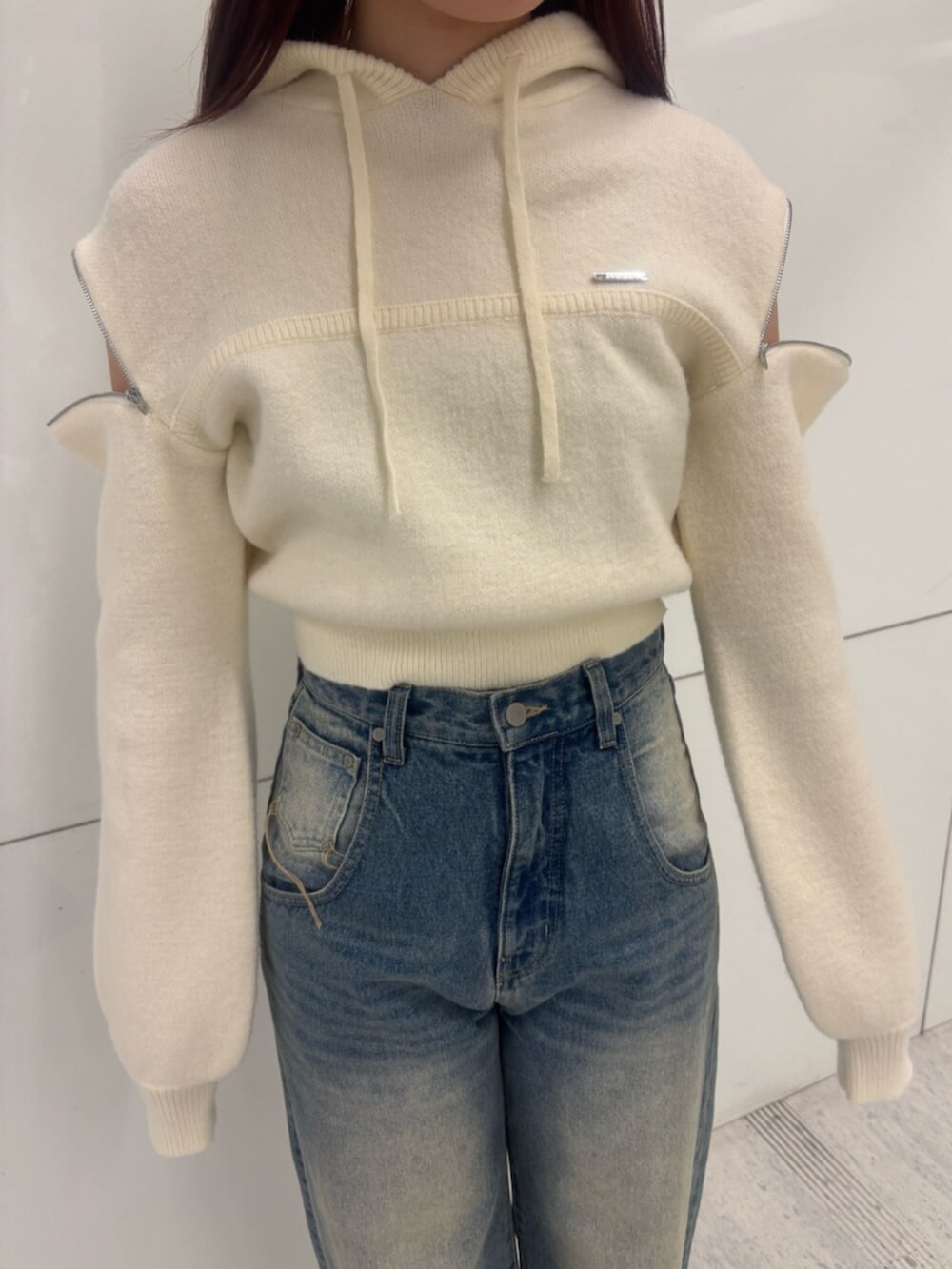 ブラック系のブーツ、ホワイト系のパーカー、ブルー系のデニムパンツを着用したレディースの冬コーディネートの4枚目の写真