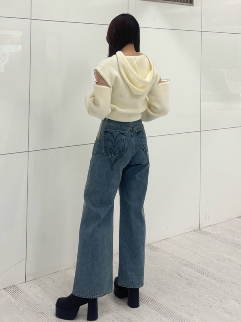 ブラック系のブーツ、ホワイト系のパーカー、ブルー系のデニムパンツを着用したレディースの冬コーディネートの2枚目の写真