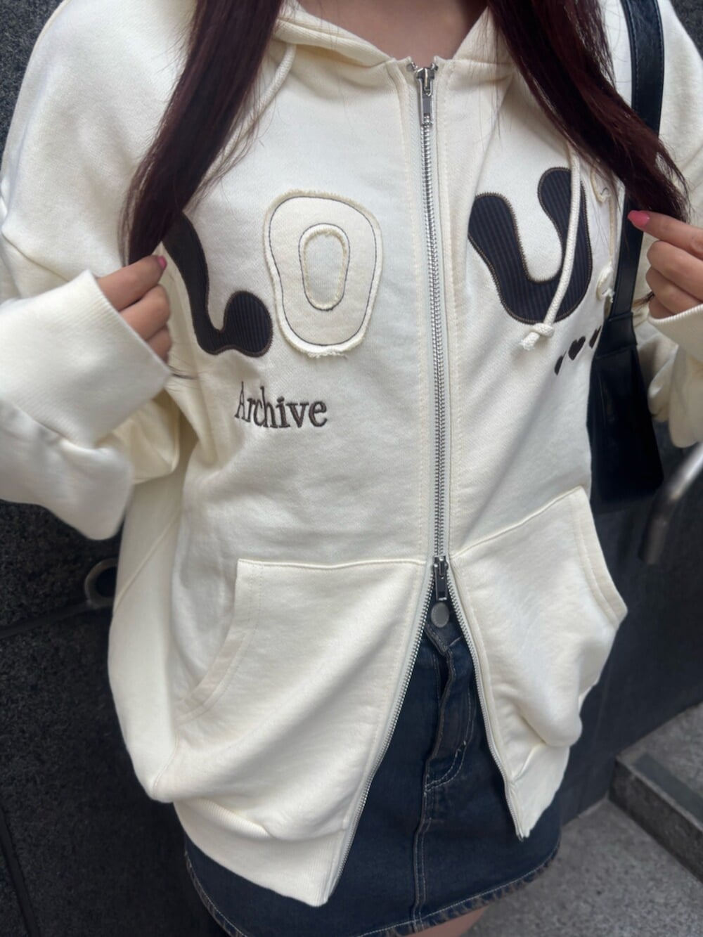 ブラック系のショルダーバッグ、ホワイト系のパーカー、ブルー系のスカートを着用したレディースの冬コーディネートの5枚目の写真