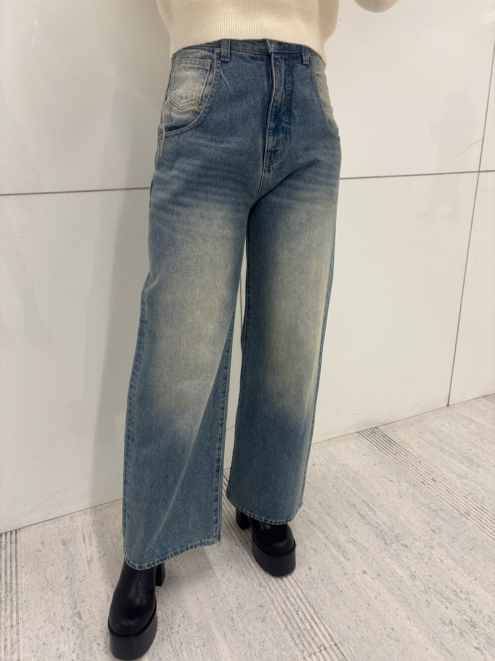 ブラック系のブーツ、ホワイト系のパーカー、ブルー系のデニムパンツを着用したレディースの冬コーディネートの8枚目の写真