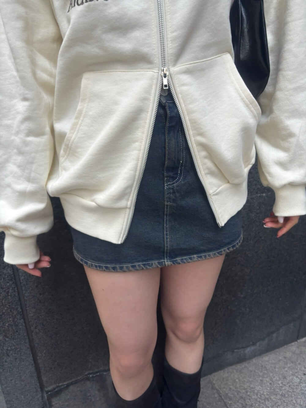 ブラック系のショルダーバッグ、ホワイト系のパーカー、ブルー系のスカートを着用したレディースの冬コーディネートの6枚目の写真