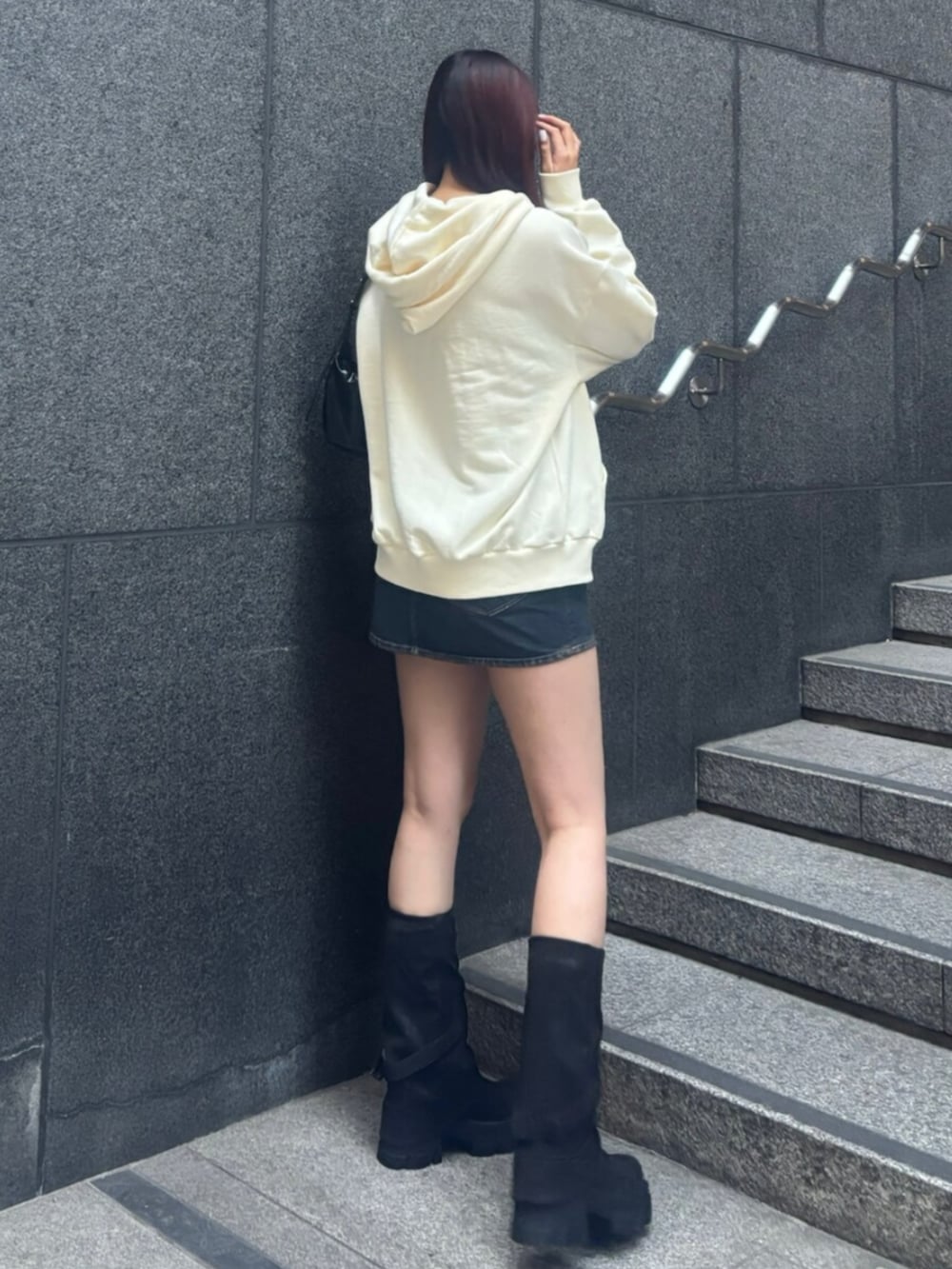 ブラック系のショルダーバッグ、ホワイト系のパーカー、ブルー系のスカートを着用したレディースの冬コーディネートの2枚目の写真