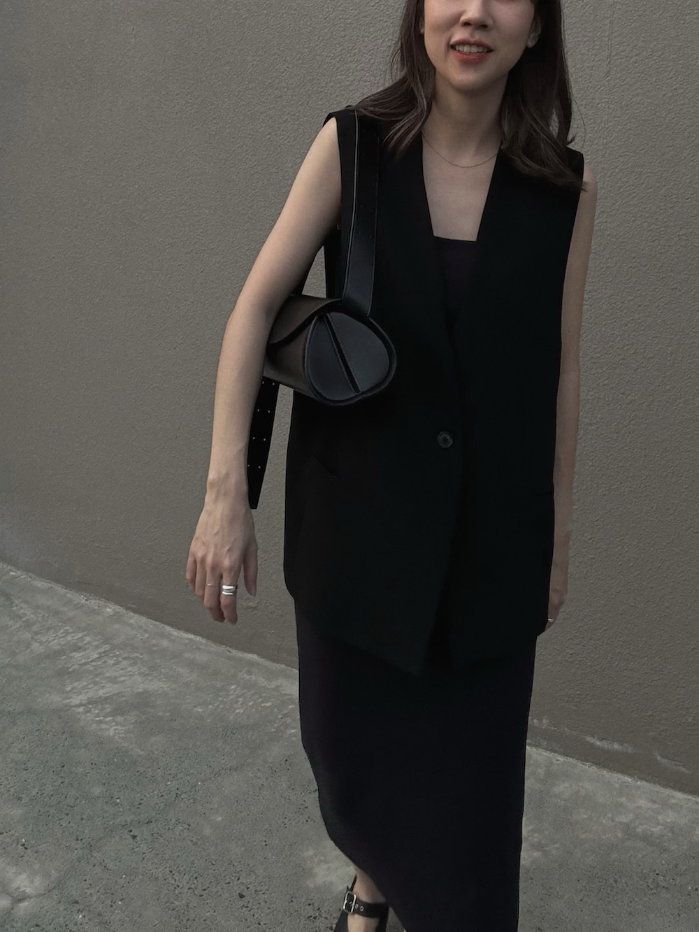 ブラック系のスーツベスト、ブラック系のハンドバッグ、ブラック系のバレエシューズを着用したレディースの春コーディネートの2枚目の写真