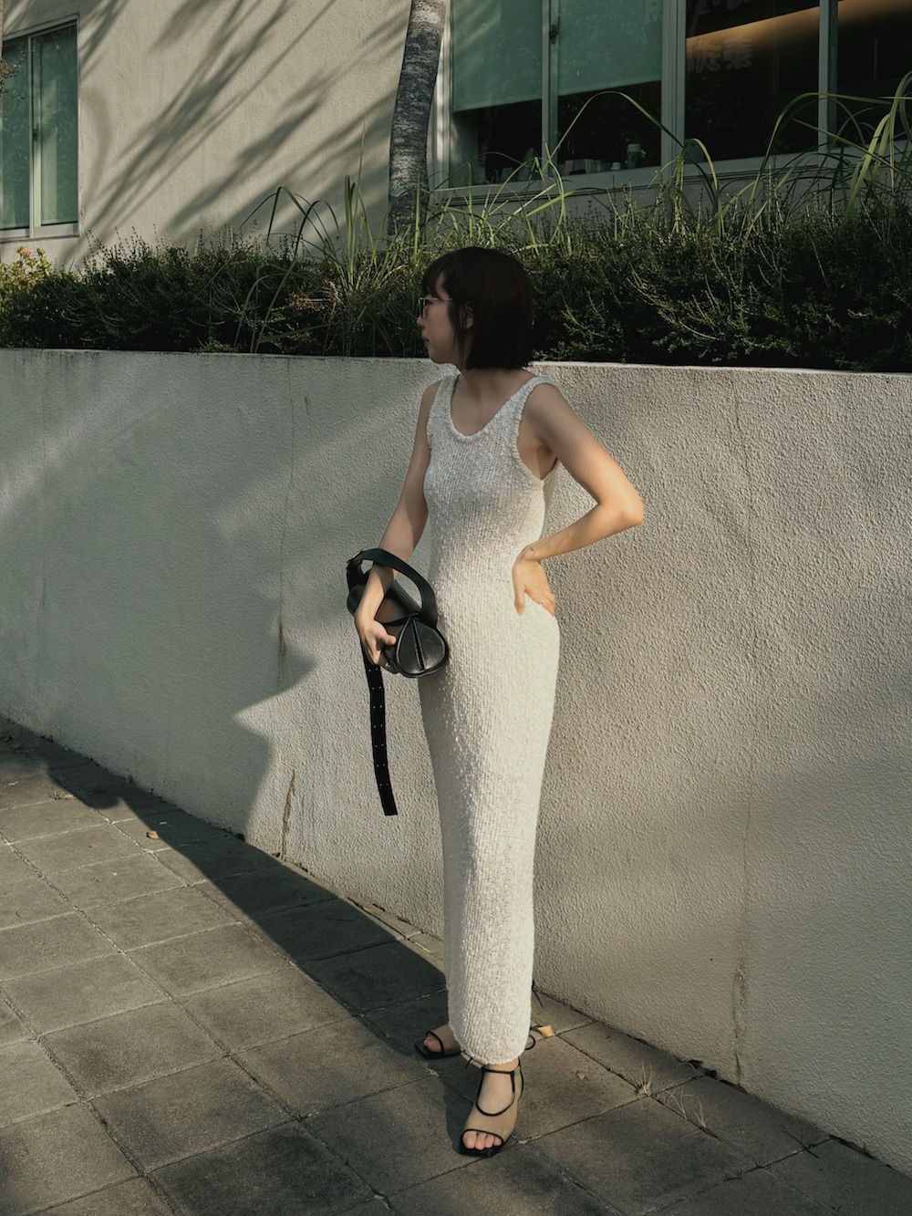 ブラック系のハンドバッグ、ブラック系のサンダルを着用したレディースの夏コーディネートの3枚目の写真