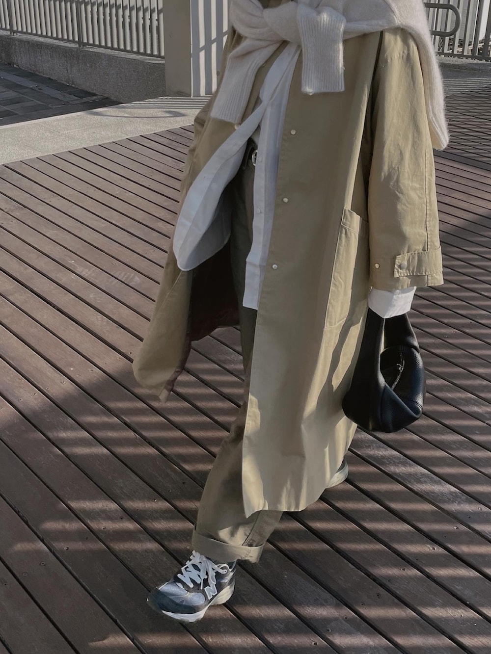 ベージュ系のトレンチコート、ホワイト系のシャツ/ブラウス、ブルー系のスニーカーを着用したレディースの冬コーディネートの3枚目の写真