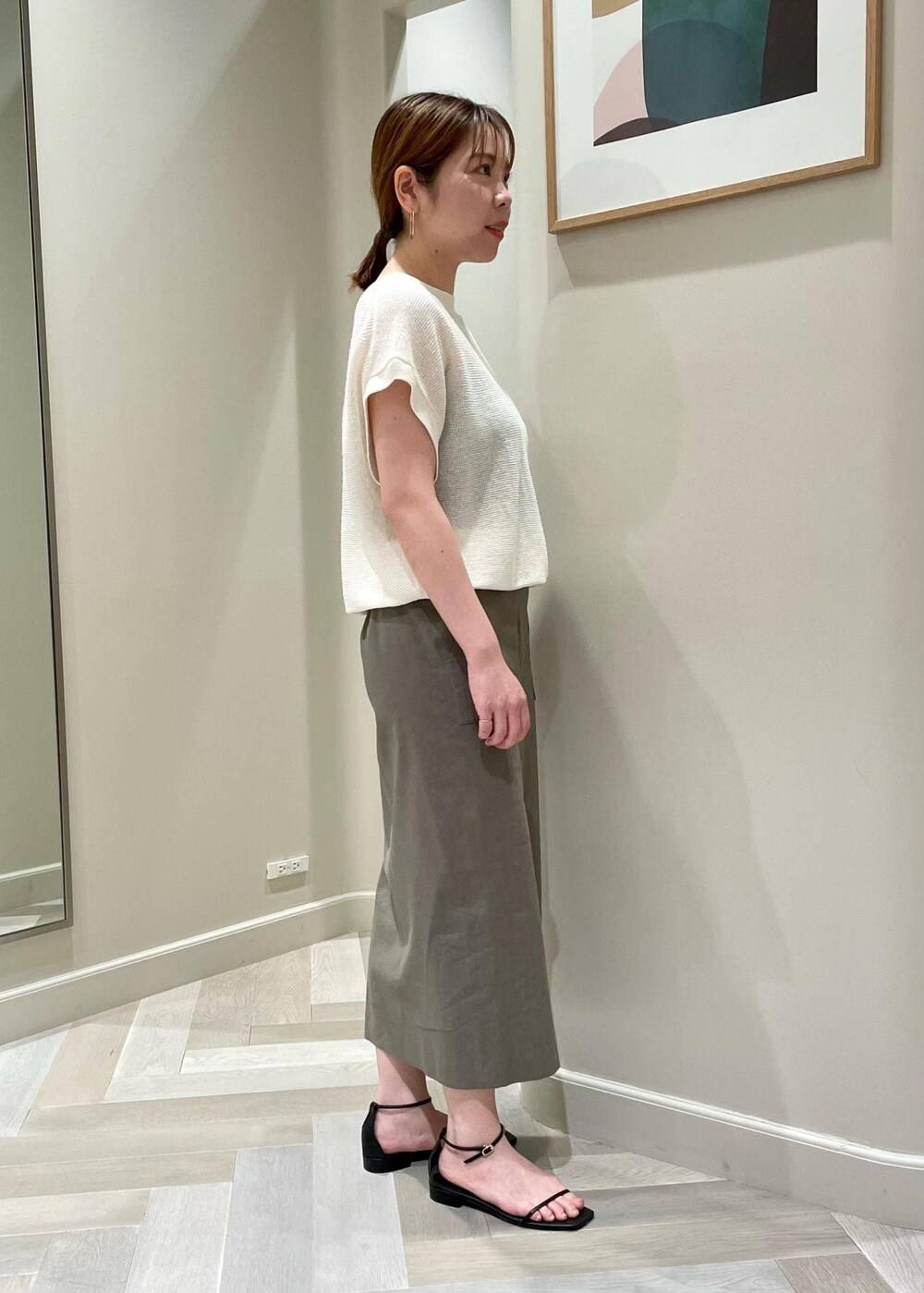 ブラック系のサンダル、グリーン系のスカート、ホワイト系のTシャツ/カットソーを着用したレディースの夏コーディネートの2枚目の写真