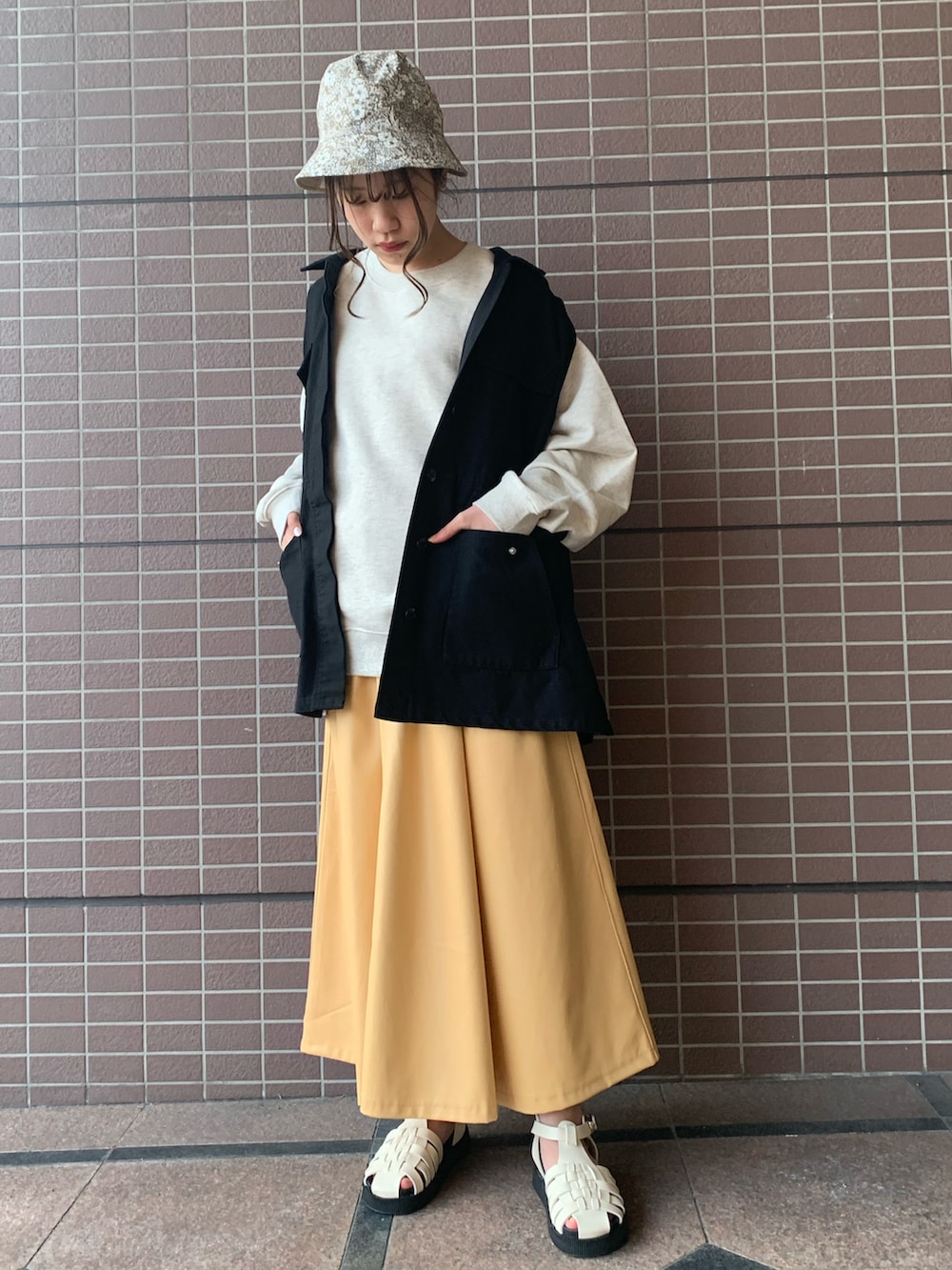 グレー系のスウェット、イエロー系のスカート、ブラック系のその他アウターを着用したレディースの春コーディネートの3枚目の写真