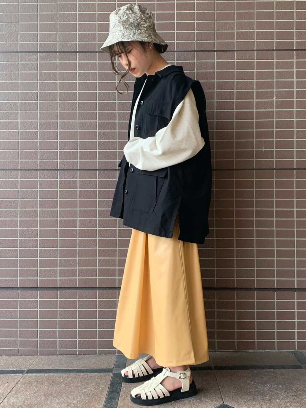 グレー系のスウェット、イエロー系のスカート、ブラック系のその他アウターを着用したレディースの春コーディネートの2枚目の写真