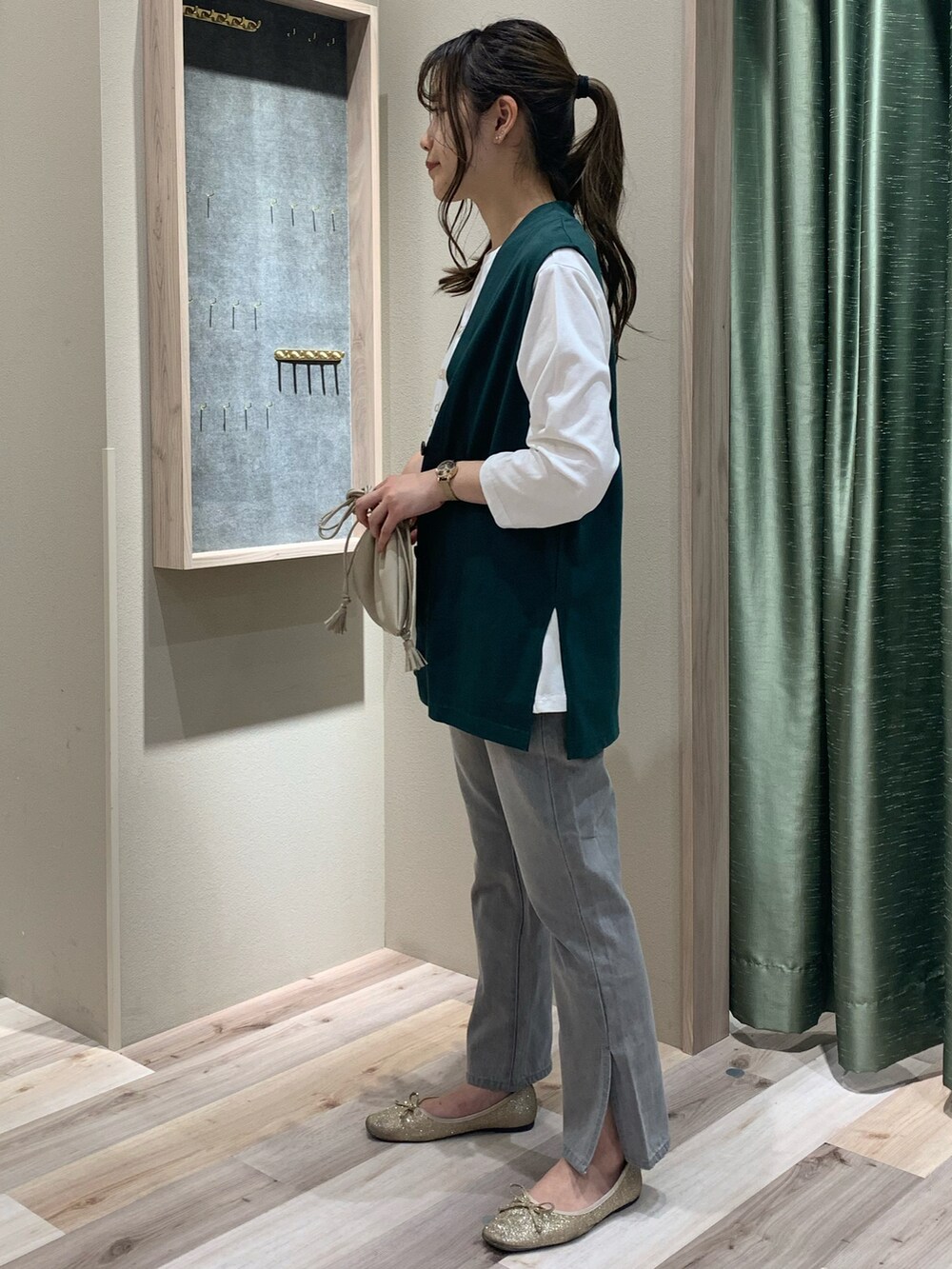 グリーン系のベスト、ホワイト系のTシャツ/カットソー、ベージュ系のショルダーバッグを着用したレディースの春コーディネートの4枚目の写真