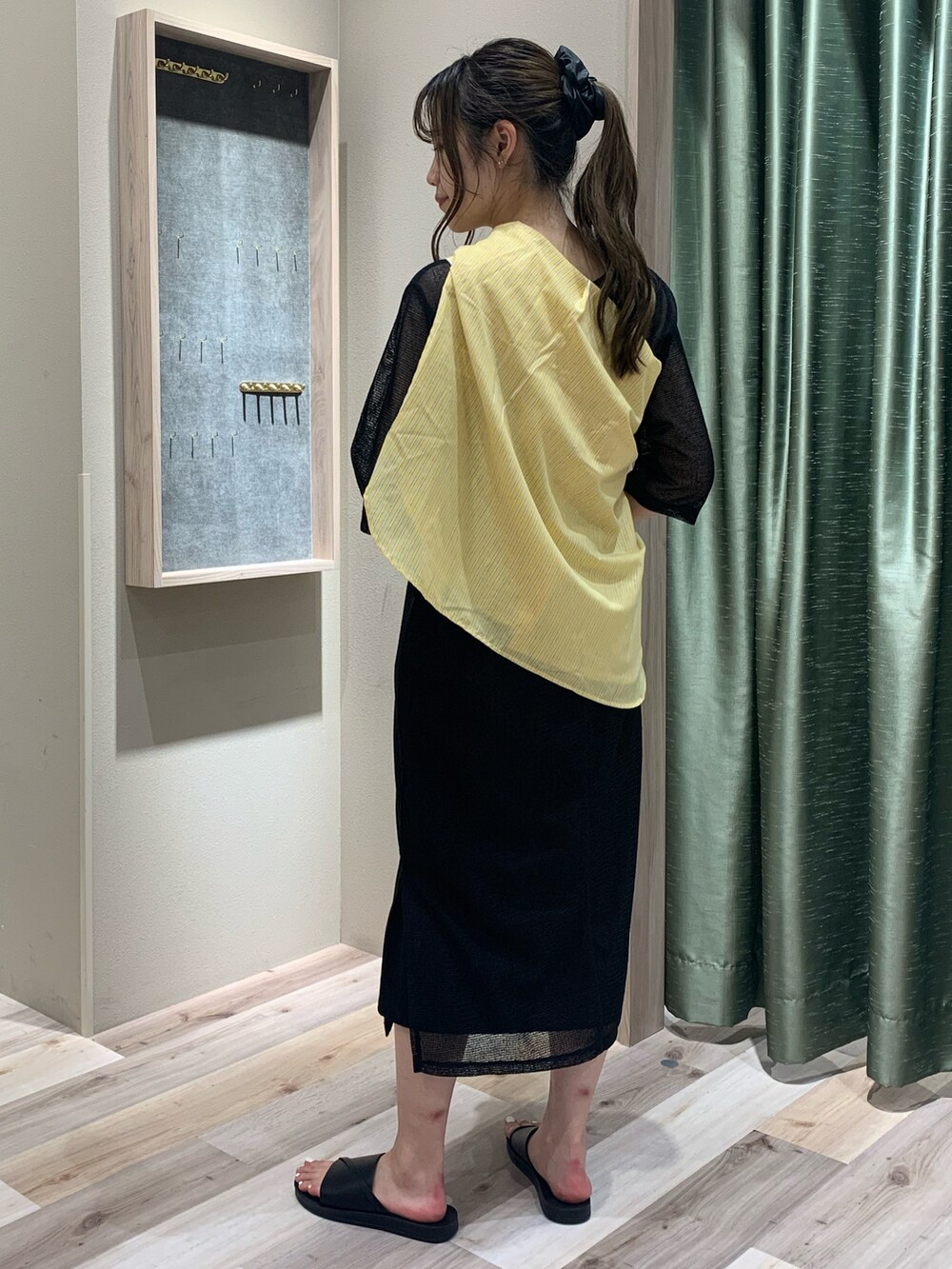 イエロー系のシャツ/ブラウス、ブラック系のワンピース、ブラック系のサンダルを着用したレディースの春コーディネートの3枚目の写真