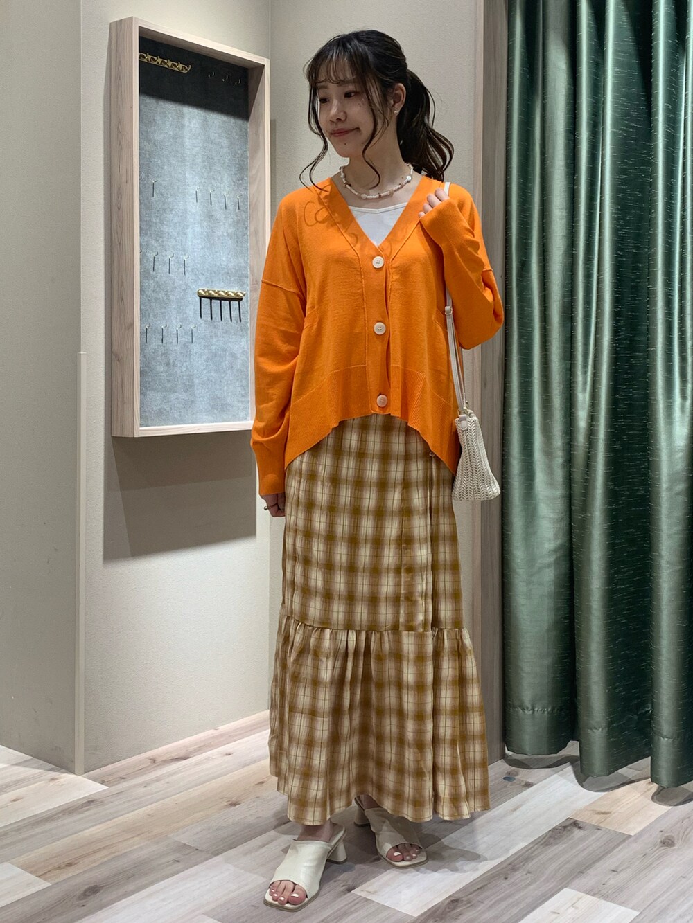 ホワイト系のキャミソール、オレンジ系のカーディガン/ボレロ、ベージュ系のスカートを着用したレディースの春コーディネートの3枚目の写真