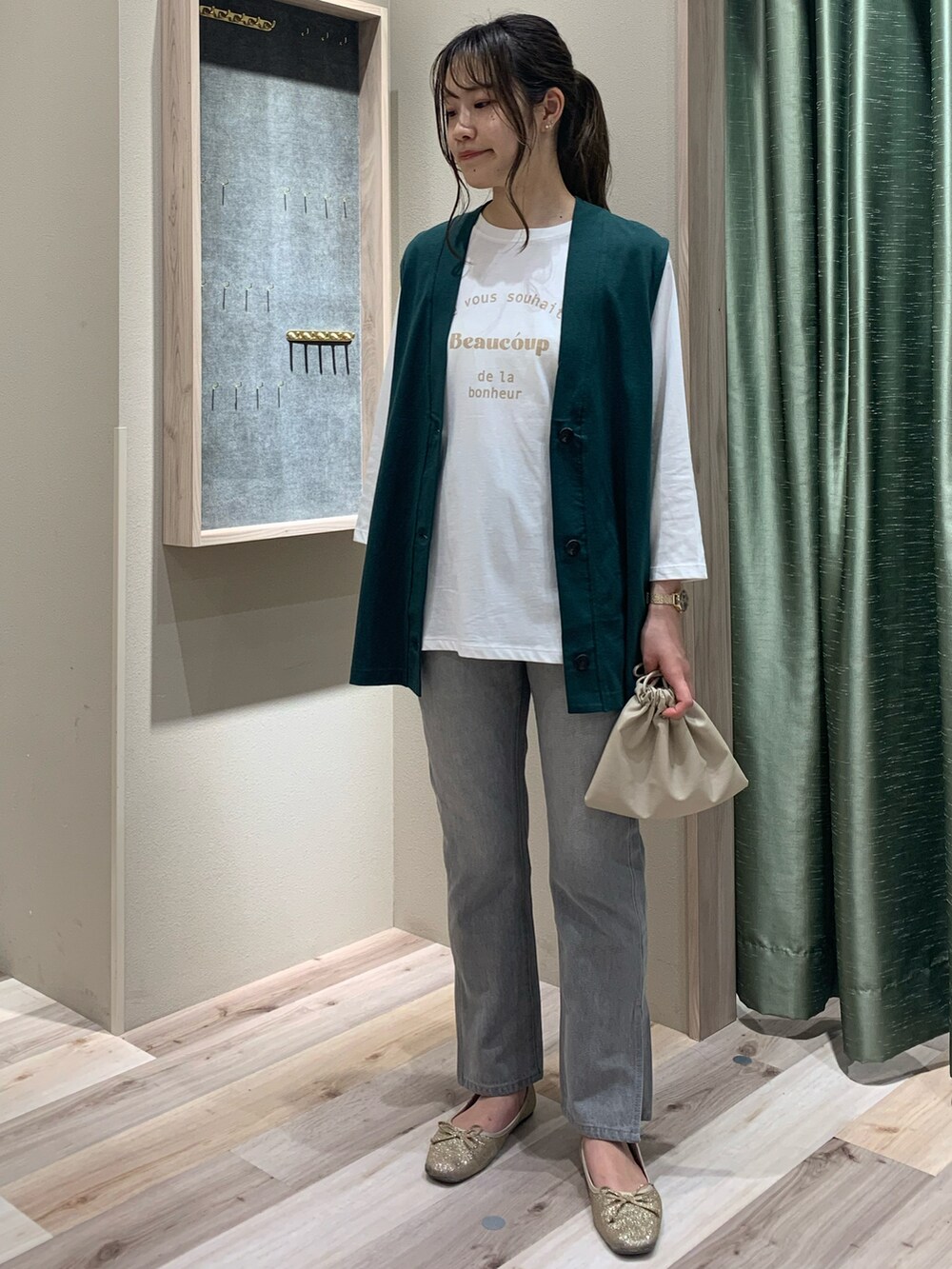 グリーン系のベスト、ホワイト系のTシャツ/カットソー、ベージュ系のショルダーバッグを着用したレディースの春コーディネートの3枚目の写真