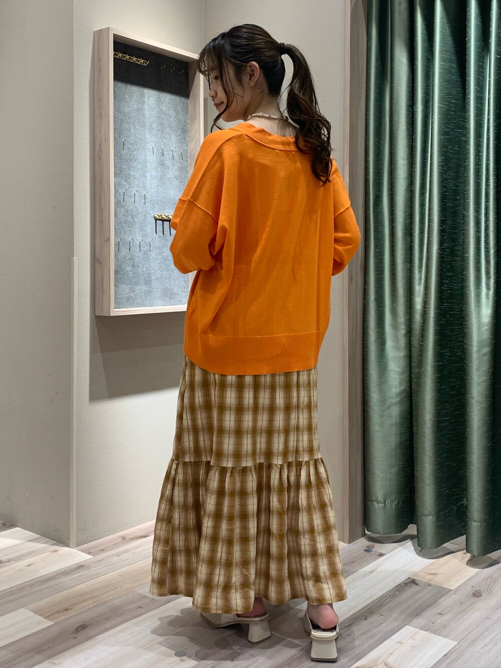 ホワイト系のキャミソール、オレンジ系のカーディガン/ボレロ、ベージュ系のスカートを着用したレディースの春コーディネートの4枚目の写真