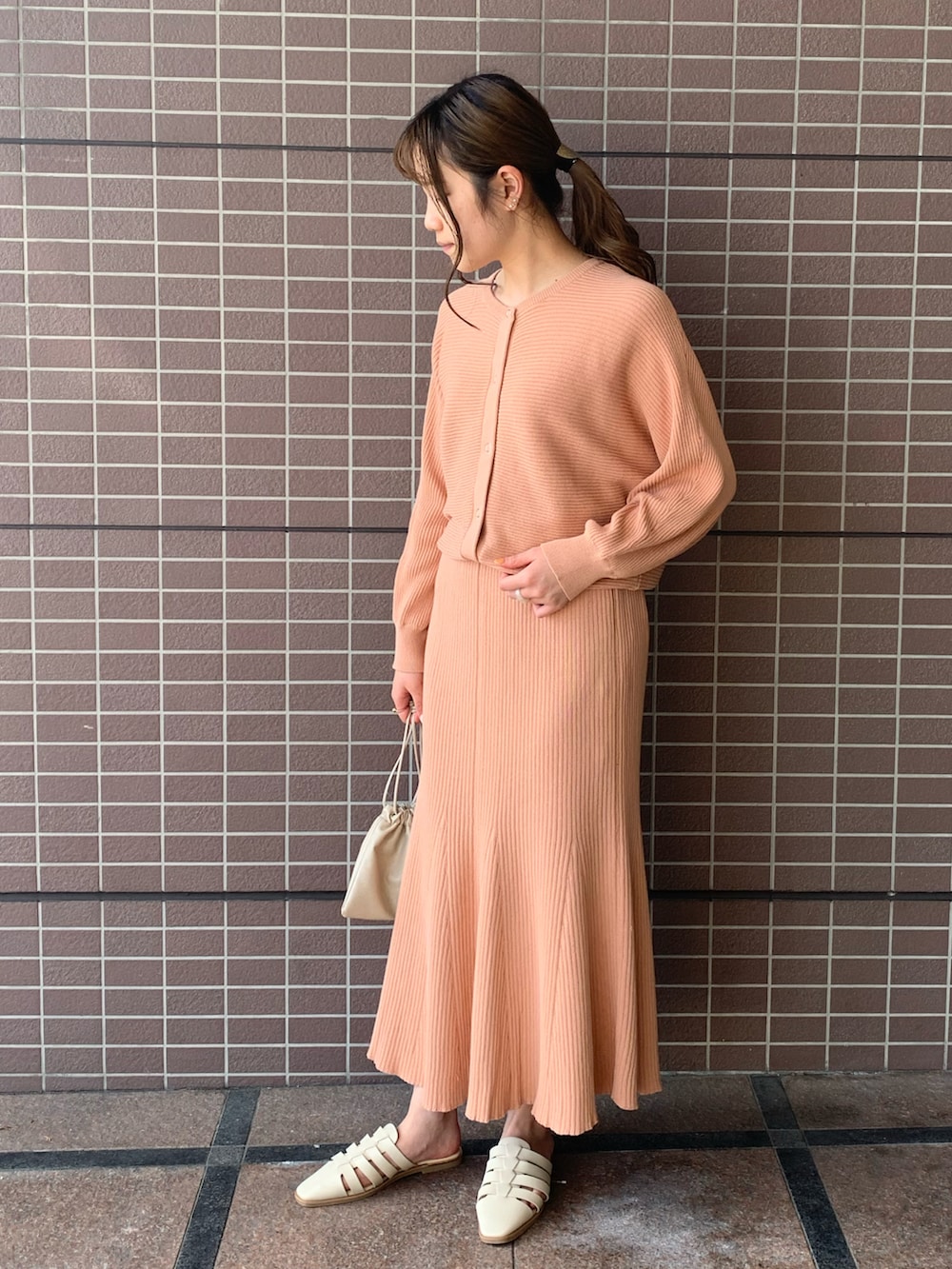 ピンク系のカーディガン/ボレロ、ピンク系のスカート、ベージュ系のショルダーバッグを着用したレディースの春コーディネートの2枚目の写真