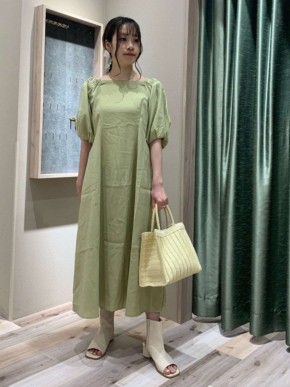 グリーン系のワンピース/ドレス、ベージュ系のトートバッグ、ホワイト系のブーツを着用したレディースの春コーディネートの2枚目の写真